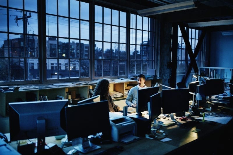 Business partners sitting at workstation in design office working late